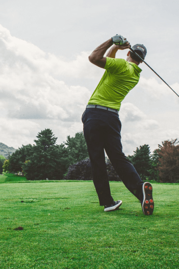 Golfer mid-swing on a green course