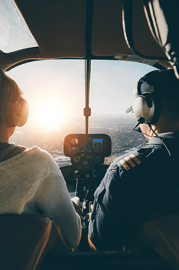 Passenger and pilot flying over the coast at sunset